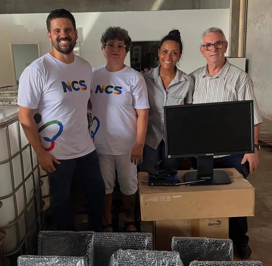 Quatro pessoas reunidas ao lado de equipamentos de informática durante uma atividade da NCS.